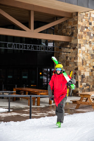 Skier in red gear leaving Mudroom in Teton Village with Kastle demo skis, just steps from Jackson Hole’s iconic Tram and slopes.