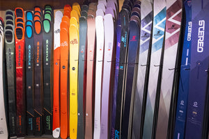 Row of skis with various designs and colors on a rack